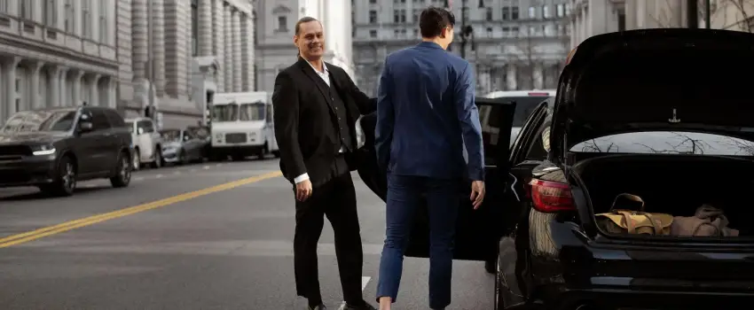 chauffeur opening the door for the passenger with a warm smile.