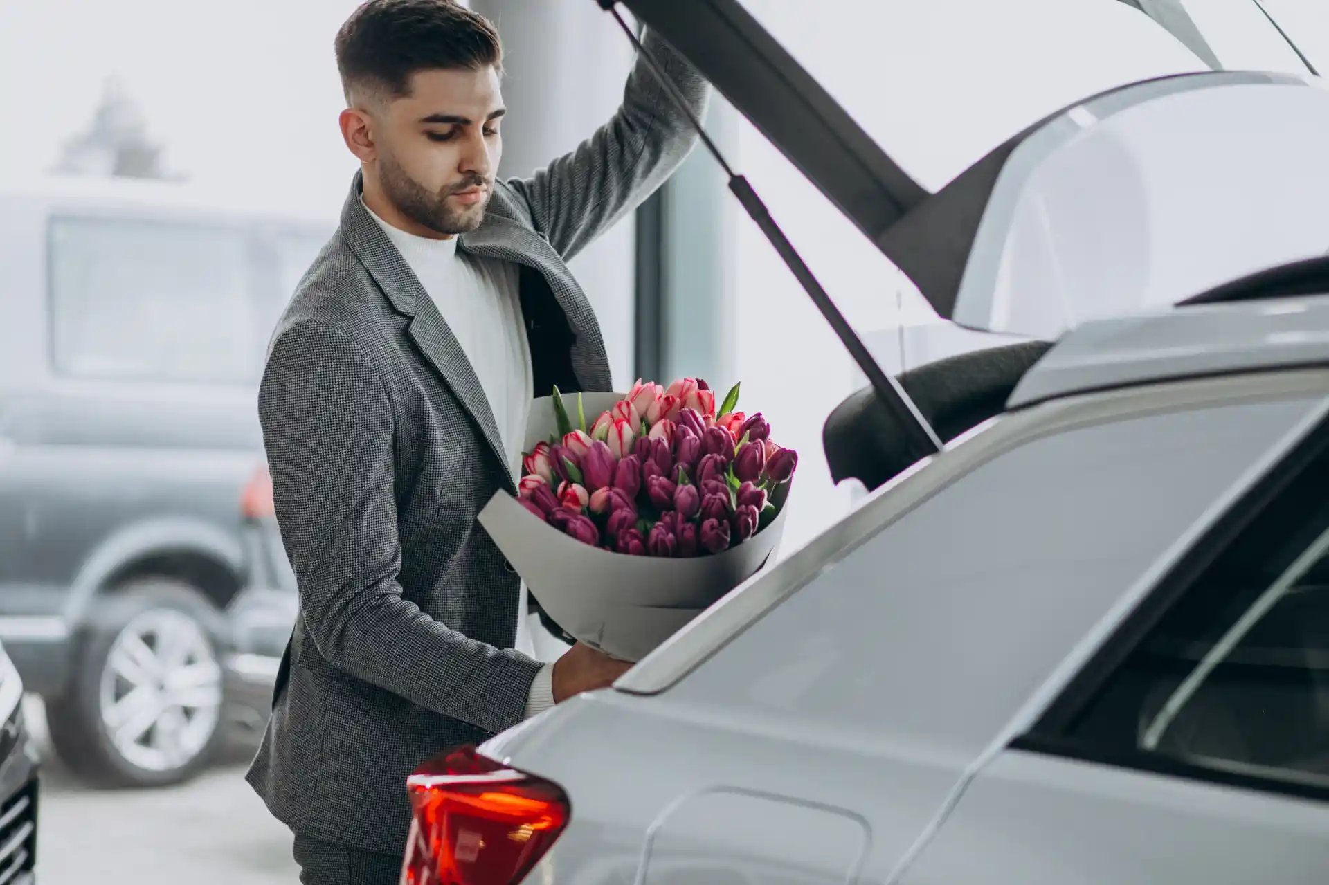 Professional chauffeur carefully loading luggage and flowers into a luxury vehicle