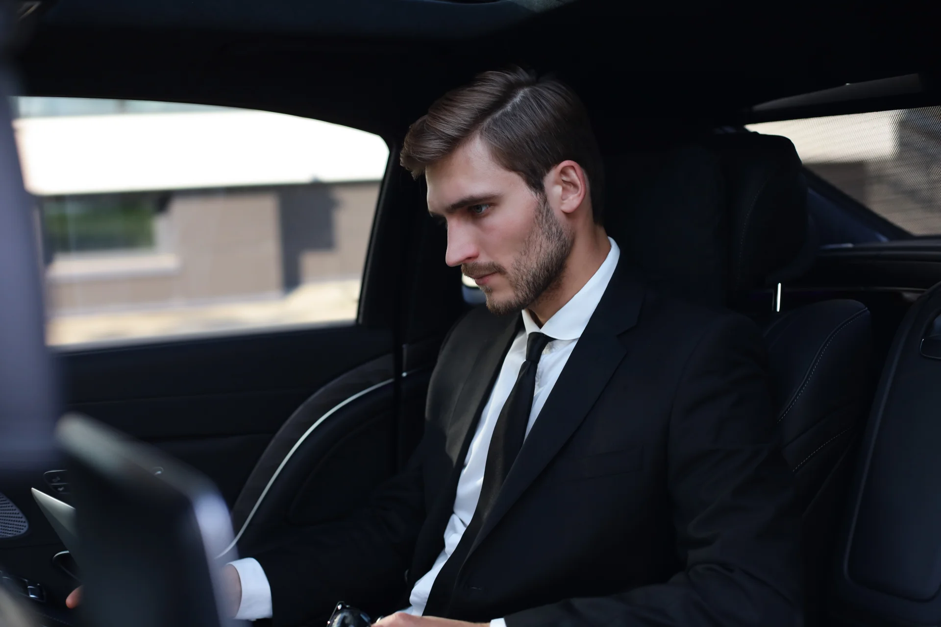 Executive working on a laptop inside a luxury chauffeur-driven car