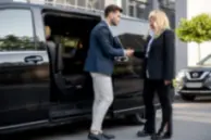 Professional chauffeur welcoming a passenger outside a luxury vehicle