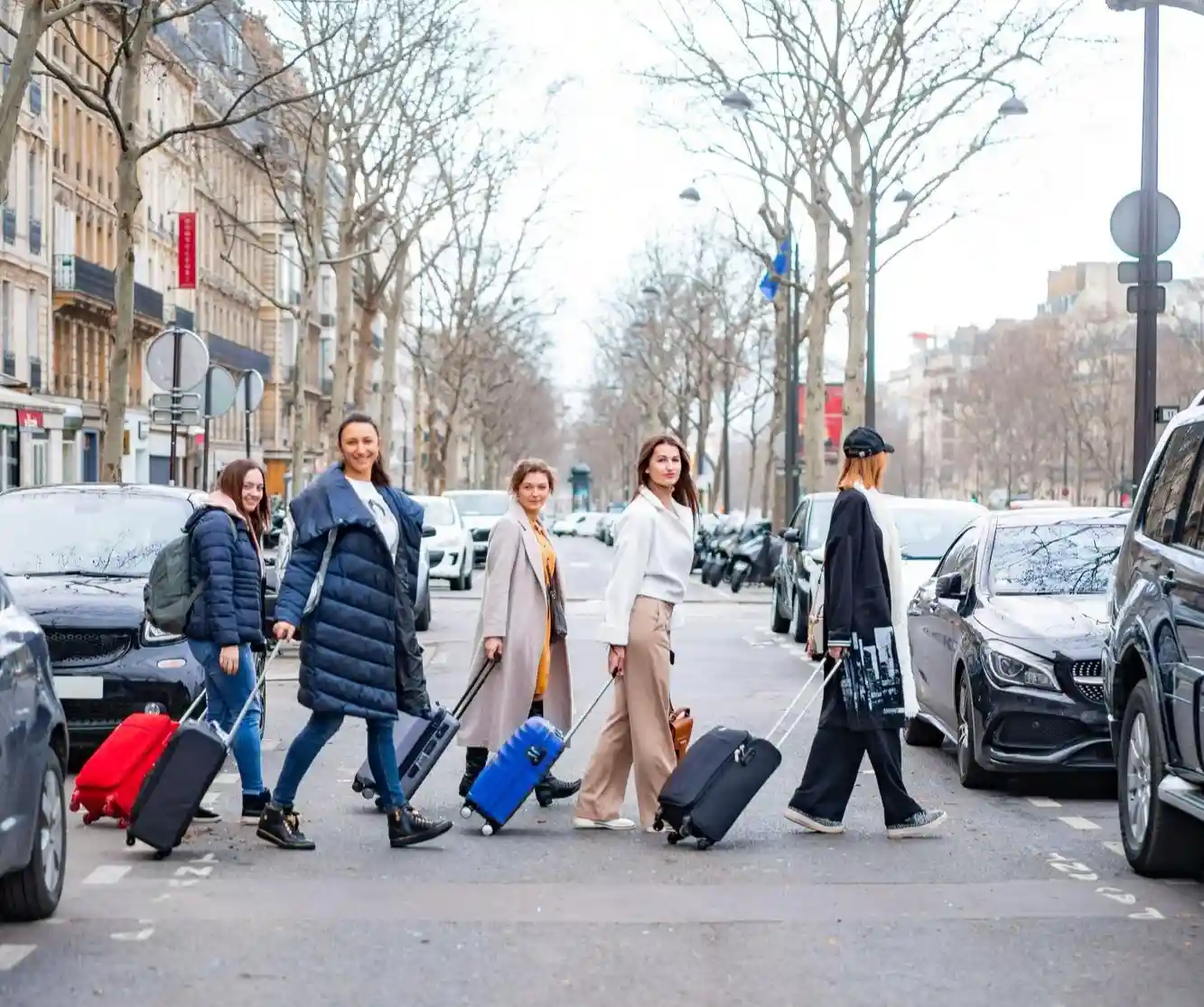 Travelers crossing a city street with rolling suitcases during an airport transfer