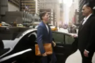 Professional chauffeur welcoming a business traveller to a luxury executive car