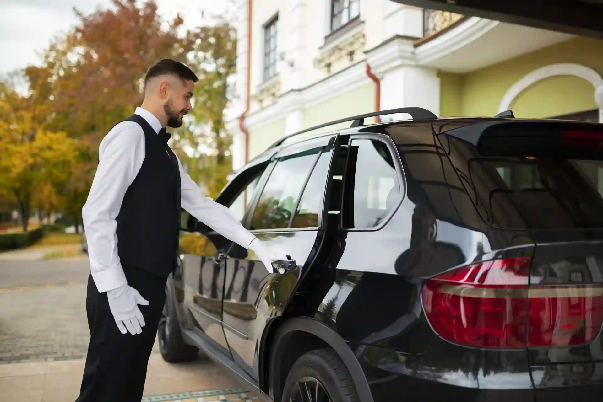A chauffeur opening the car door of a luxury car for the passenger