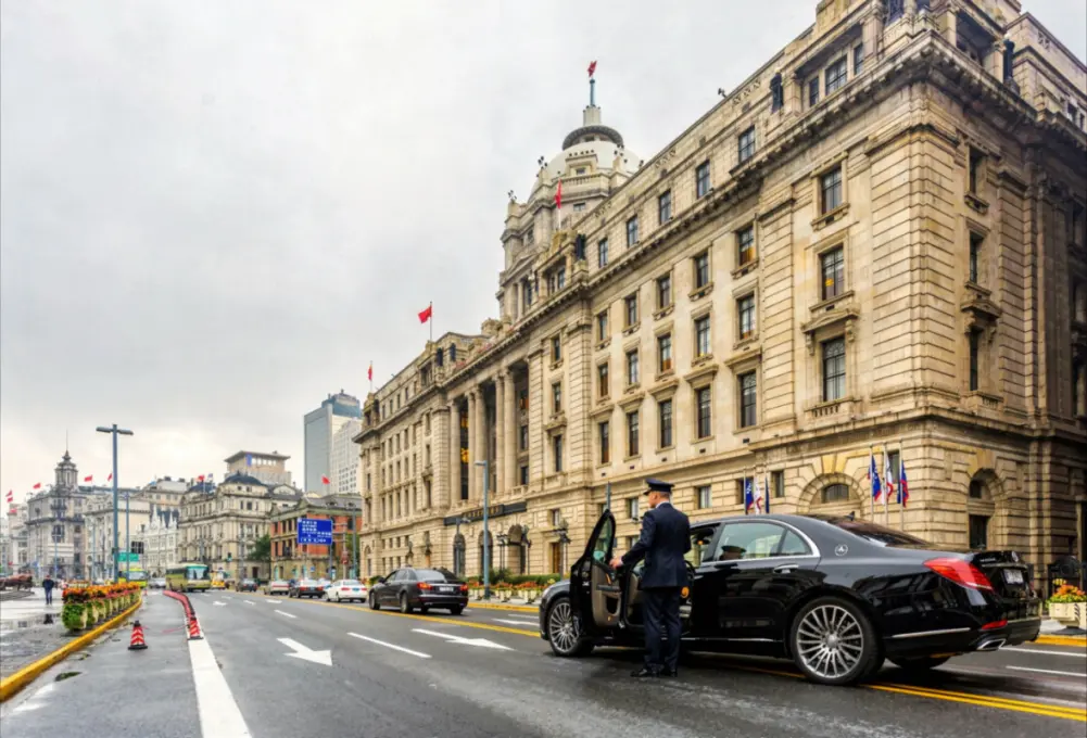 Luxury chauffeur opening SUV door for female passenger during premium private transfer service