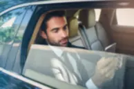 Executive using a tablet inside a luxury chauffeur-driven car