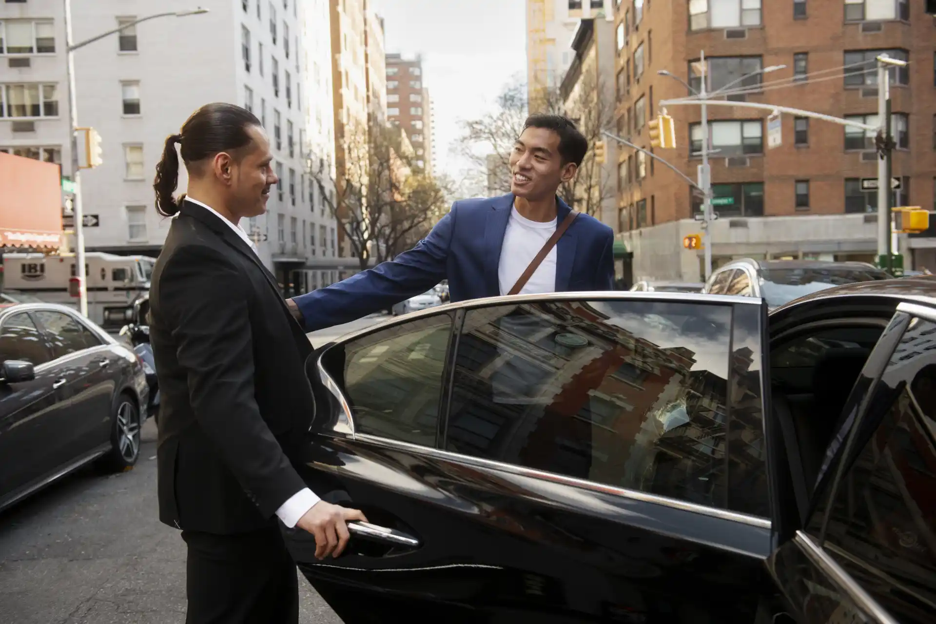 Professional chauffeur welcoming a business traveller to a luxury executive car